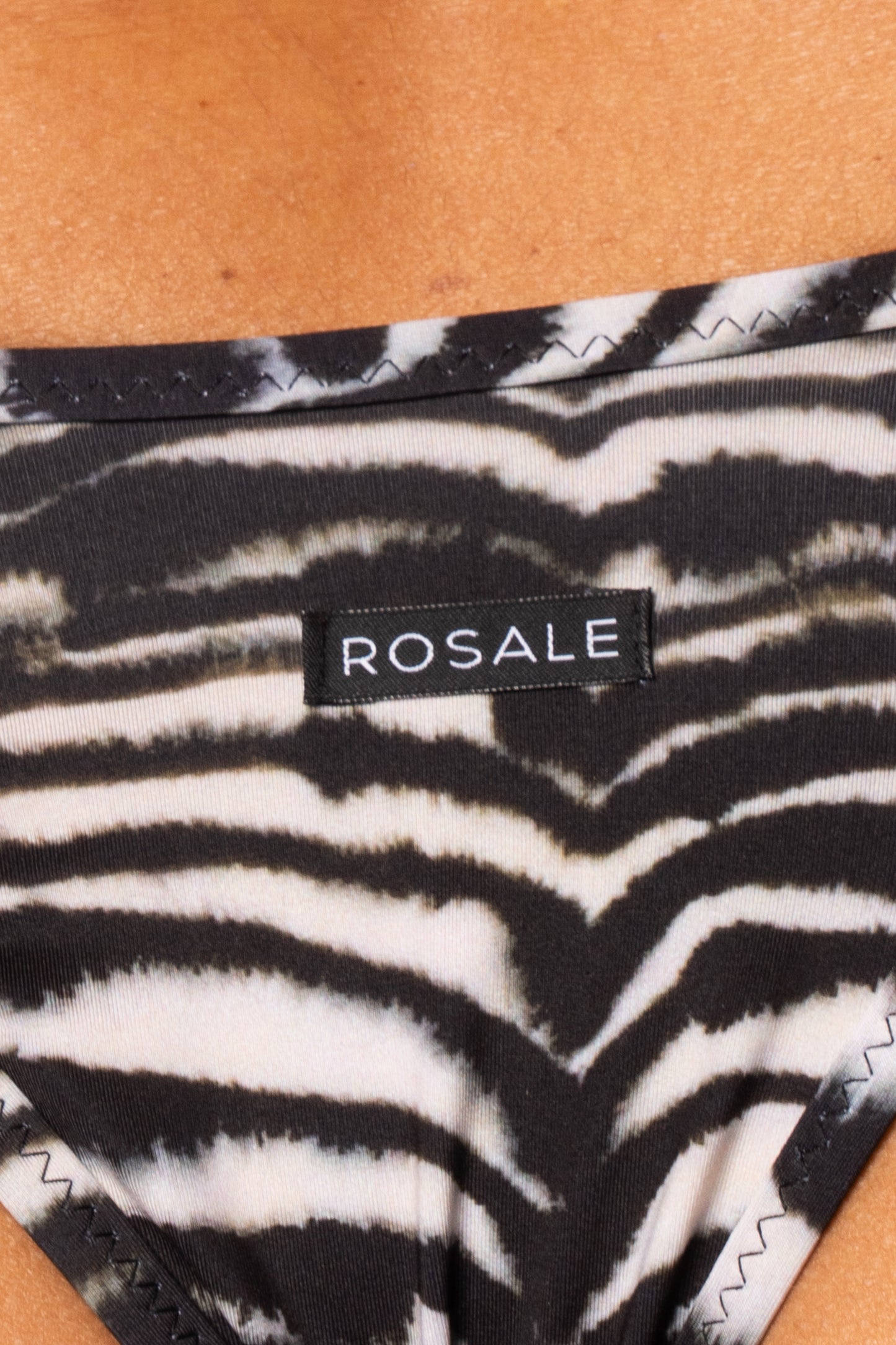 Dettaglio del retro dello slip con stampa zebra bianco e nero con etichetta nera del logo Rosale cucita sul tessuto