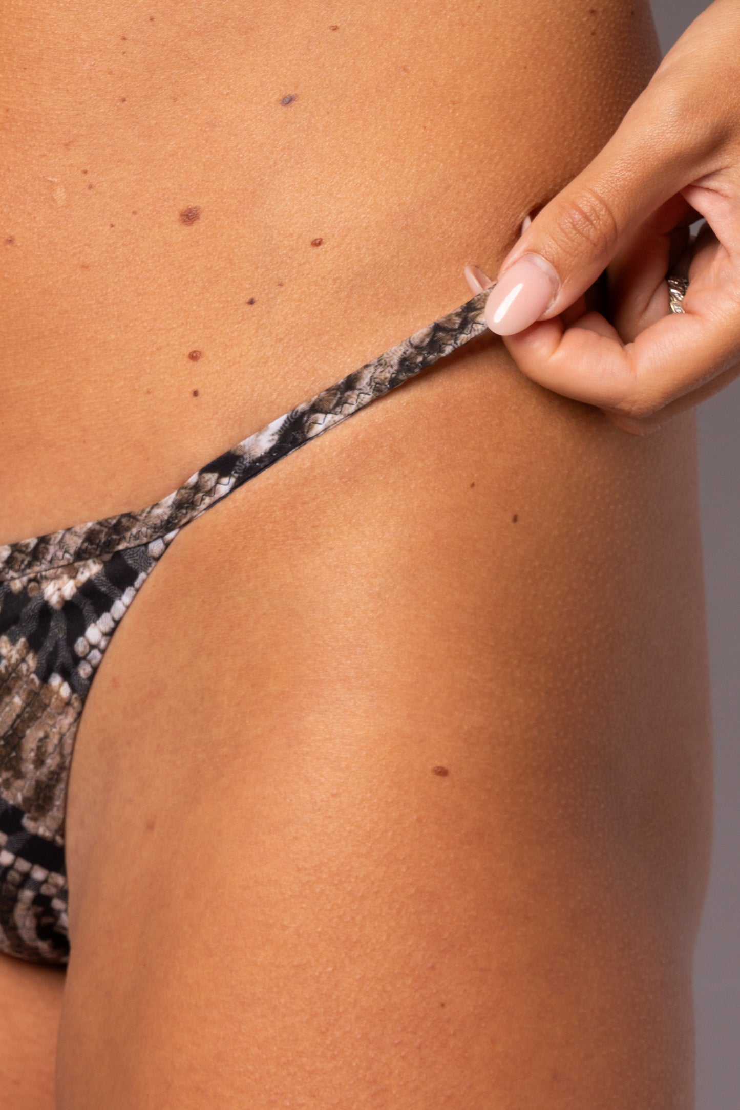 Dettaglio laterale slip bikini Rosale con stampa pitonata neutra e laccetto sottile